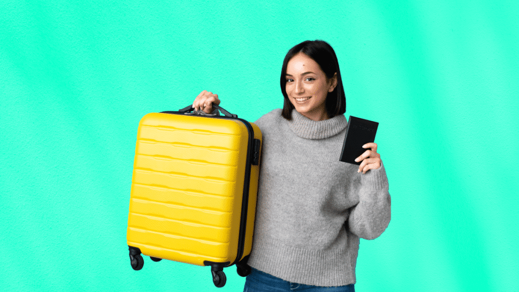 Jeune femme prête à partir en déplacement pro, tenant une valise jaune vive et un passeport, avec un sourire détendu.