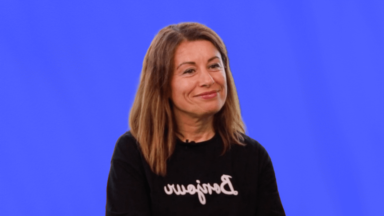 Arzu Djaouani, assistante de direction générale chez Naf Naf, souriante, témoigne de son expérience client, sur fond bleu uni.
