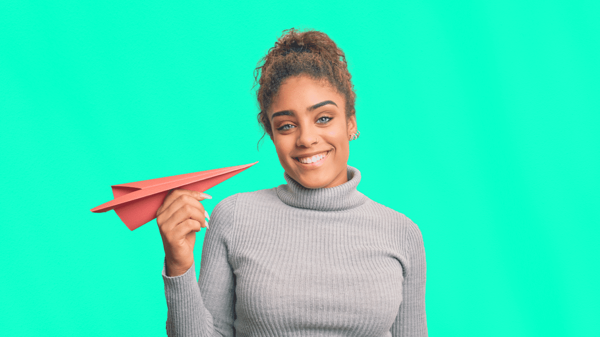 Femme souriante tenant un avion en papier, illustrant la politique voyages d'entreprise et l’organisation simplifiée des déplacements professionnels.