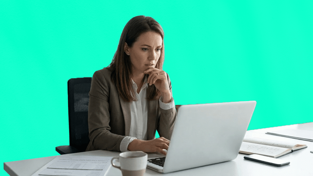 Une professionnelle pensive travaille sur son ordinateur portable dans un bureau, illustrant la rigueur nécessaire pour la gestion des voyages d'affaires.