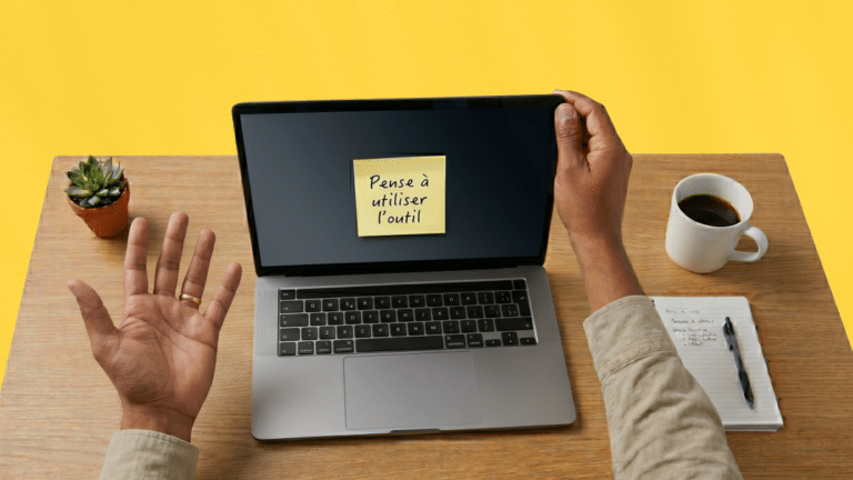 Photo vue du dessus d'un ordinateur portable ouvert affichant un post-it avec l'inscription "Pense à utiliser l'outil", illustrant le taux d'adoption outil de gestion de voyage d'affaires.