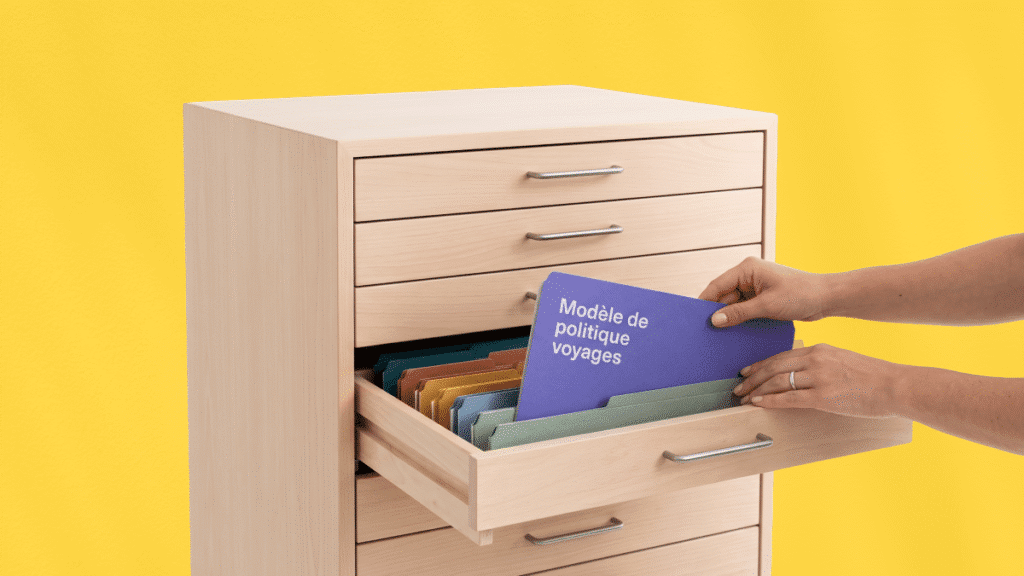 Une personne range un dossier bleu intitulé « Modèle de politique voyages » dans un tiroir de bureau ouvert contenant d'autres dossiers colorés, sur un fond jaune uni.