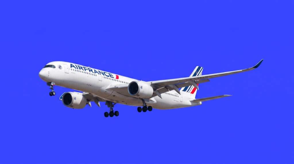 Un avion de la compagnie Air France en plein vol sur fond bleu vif, illustrant la réservation de vols via l'intégration Supertripper et Air France-KLM.
