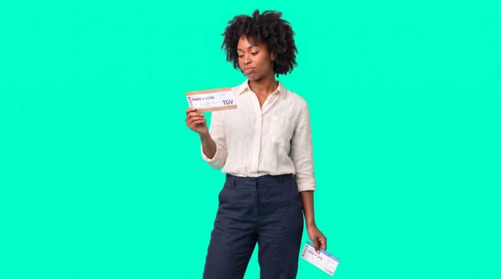 Une salariée compare un billet de TGV Paris-Lyon et une carte d'embarquement pour choisir entre l'avion et le train en déplacement professionnel.